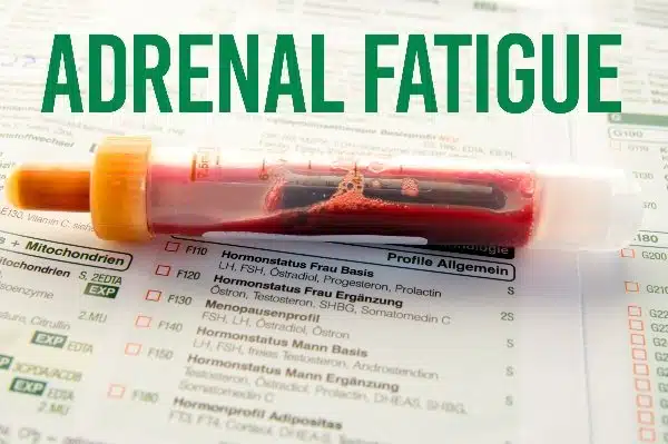 A blood vial sits on a medical checklist with the words adrenal fatigue written over the top.