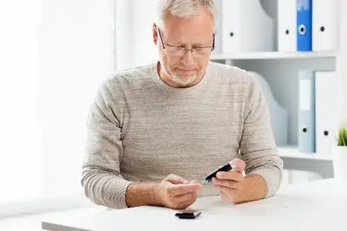 A man with white hair checks his blood sugar levels due to diabetes.